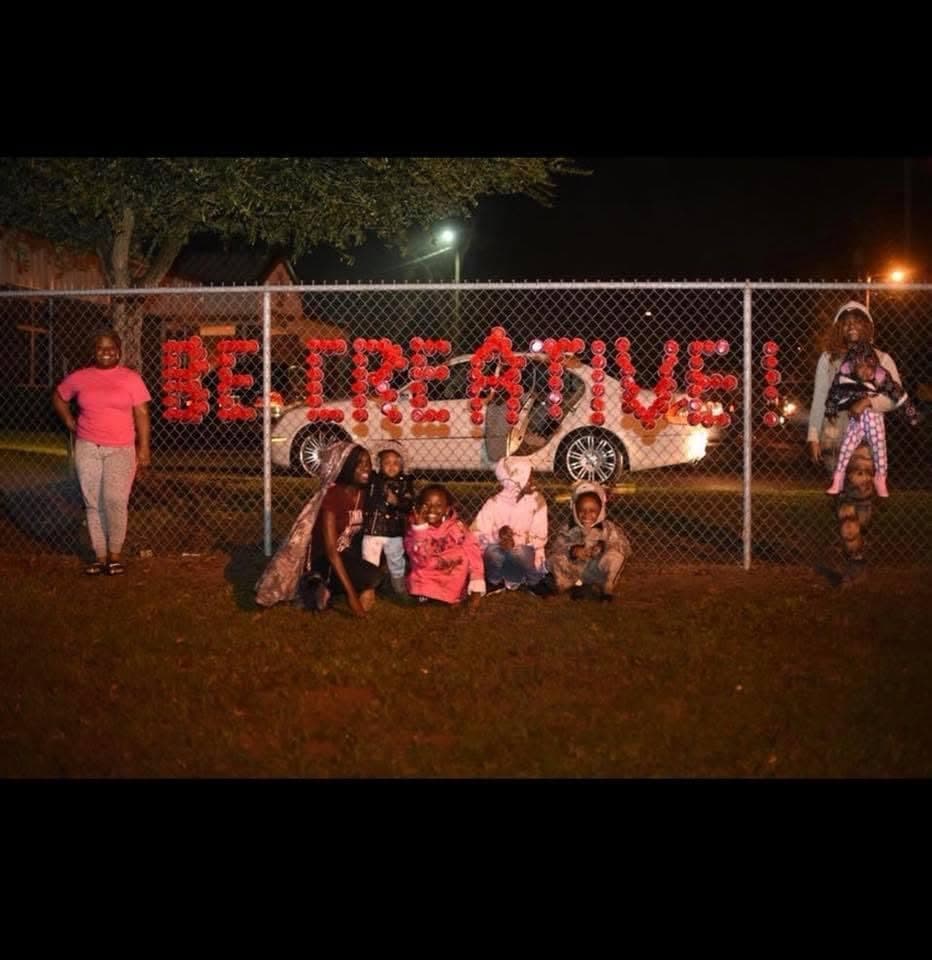 Community group at night in front of BE CREATIVE LA spelled in red cups