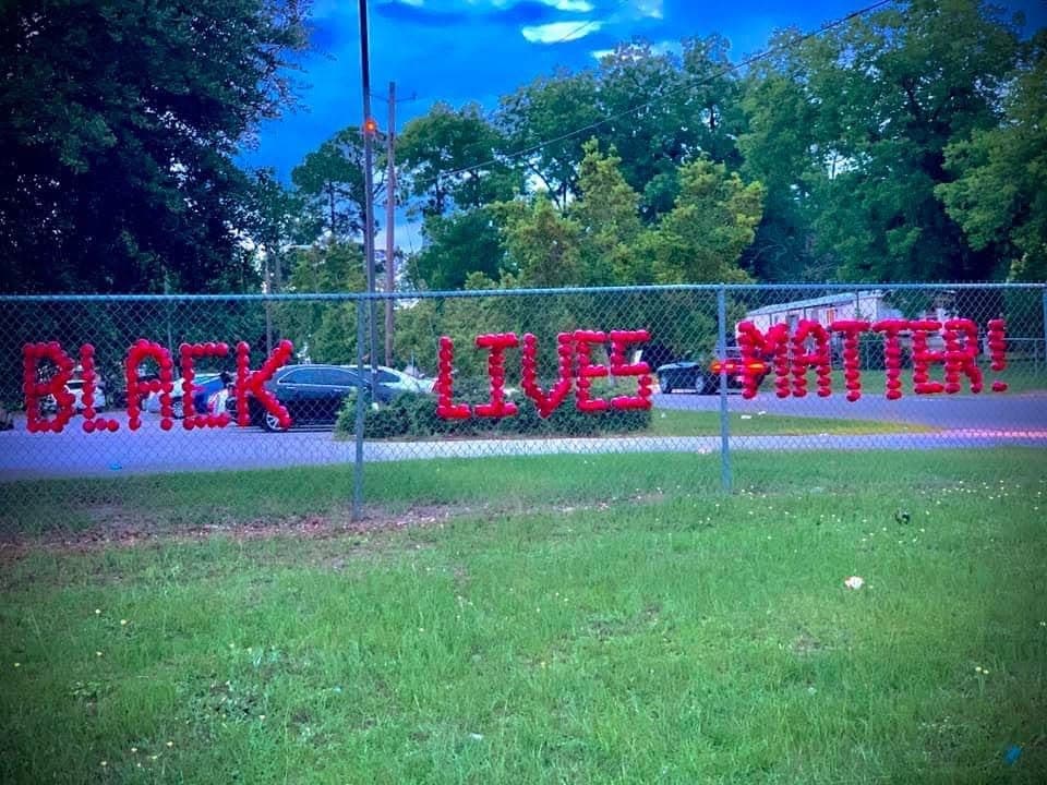 Black Lives Matter spelled in red cups on a chain-link fence