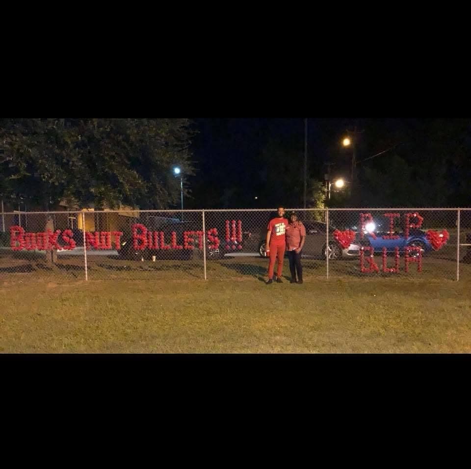 Fence installation reading Books Not Bullets and R.I.P. Slim in red cups