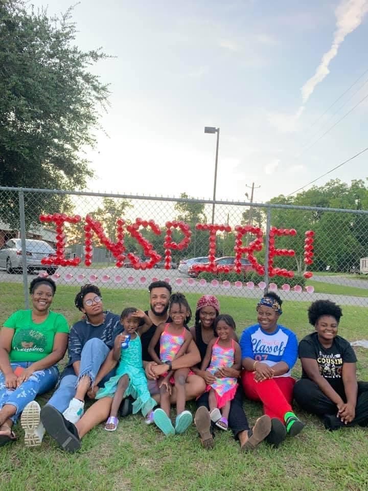 Community group in front of a fence with INSPIRE spelled in red cups