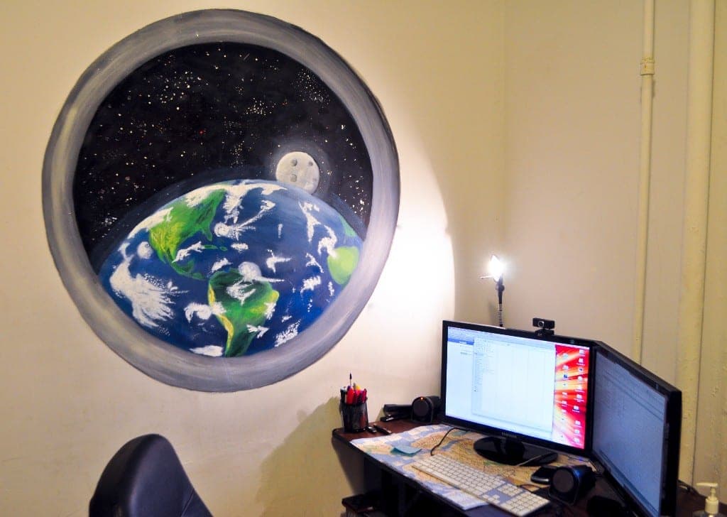 Earth porthole mural painted as a circular window above a desk, with Earth and moon in deep space.
