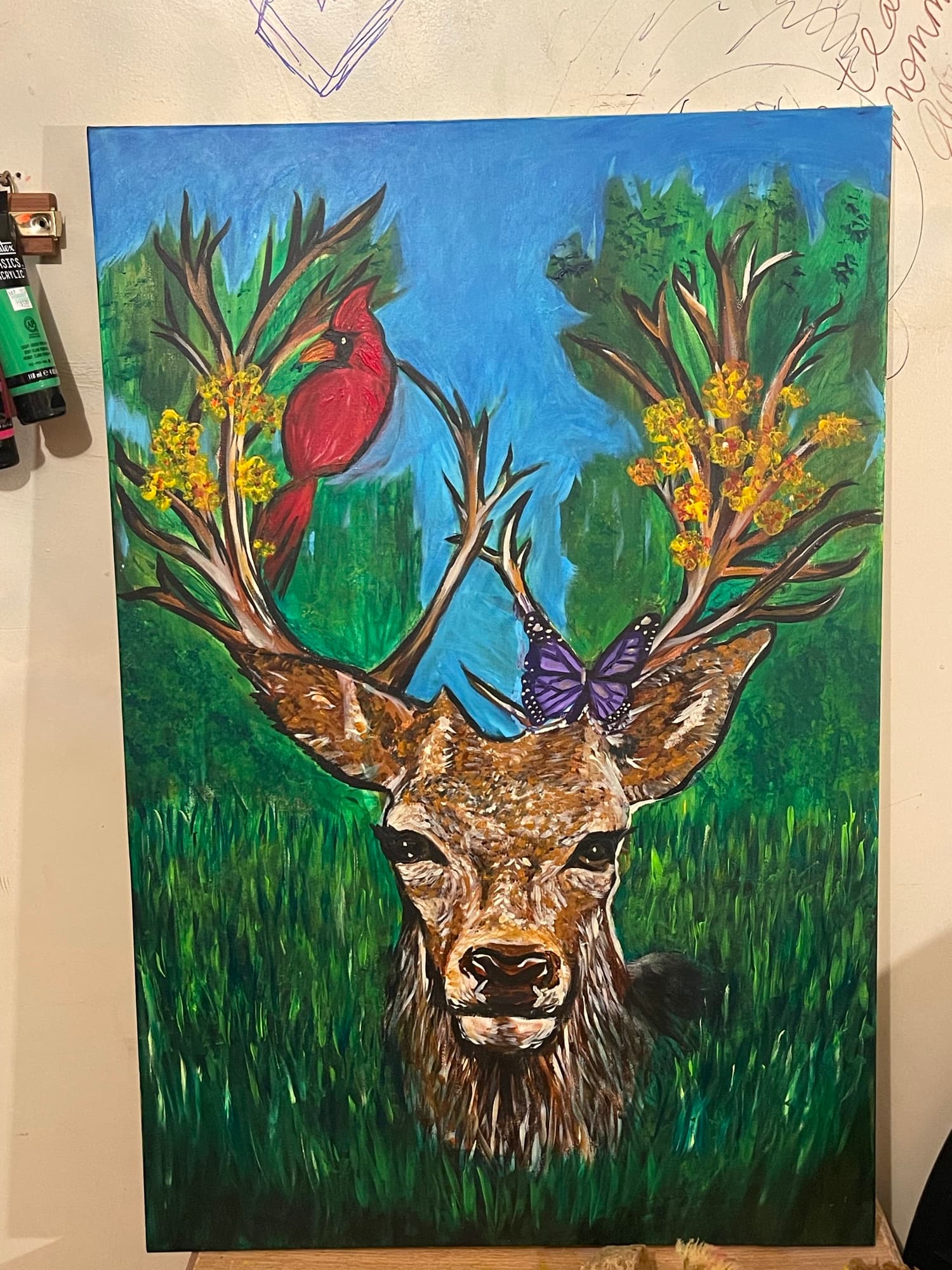 Deer Adorned, finished painting with a red cardinal on one antler and a purple butterfly on the other.